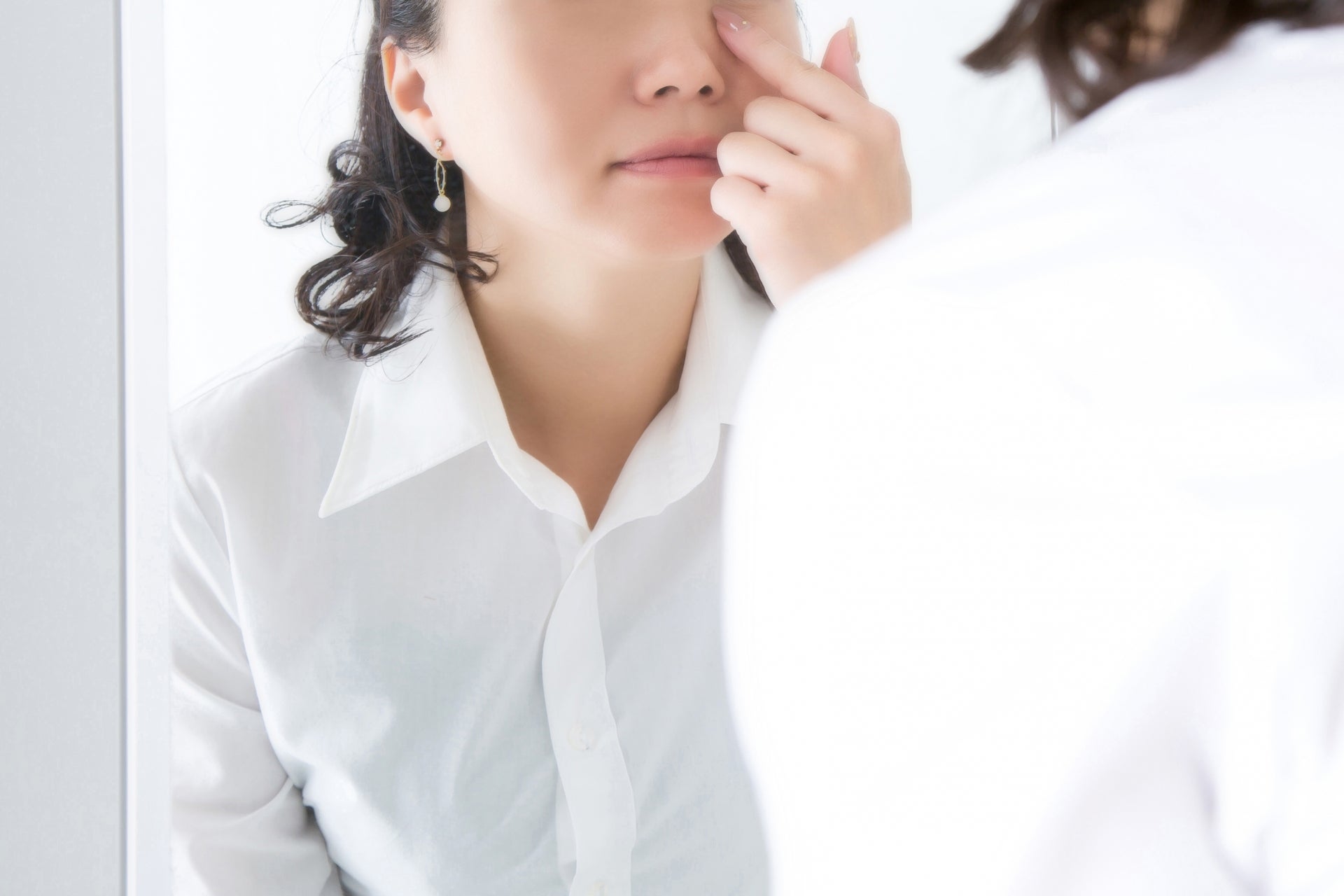 鏡で目をチェックする女性