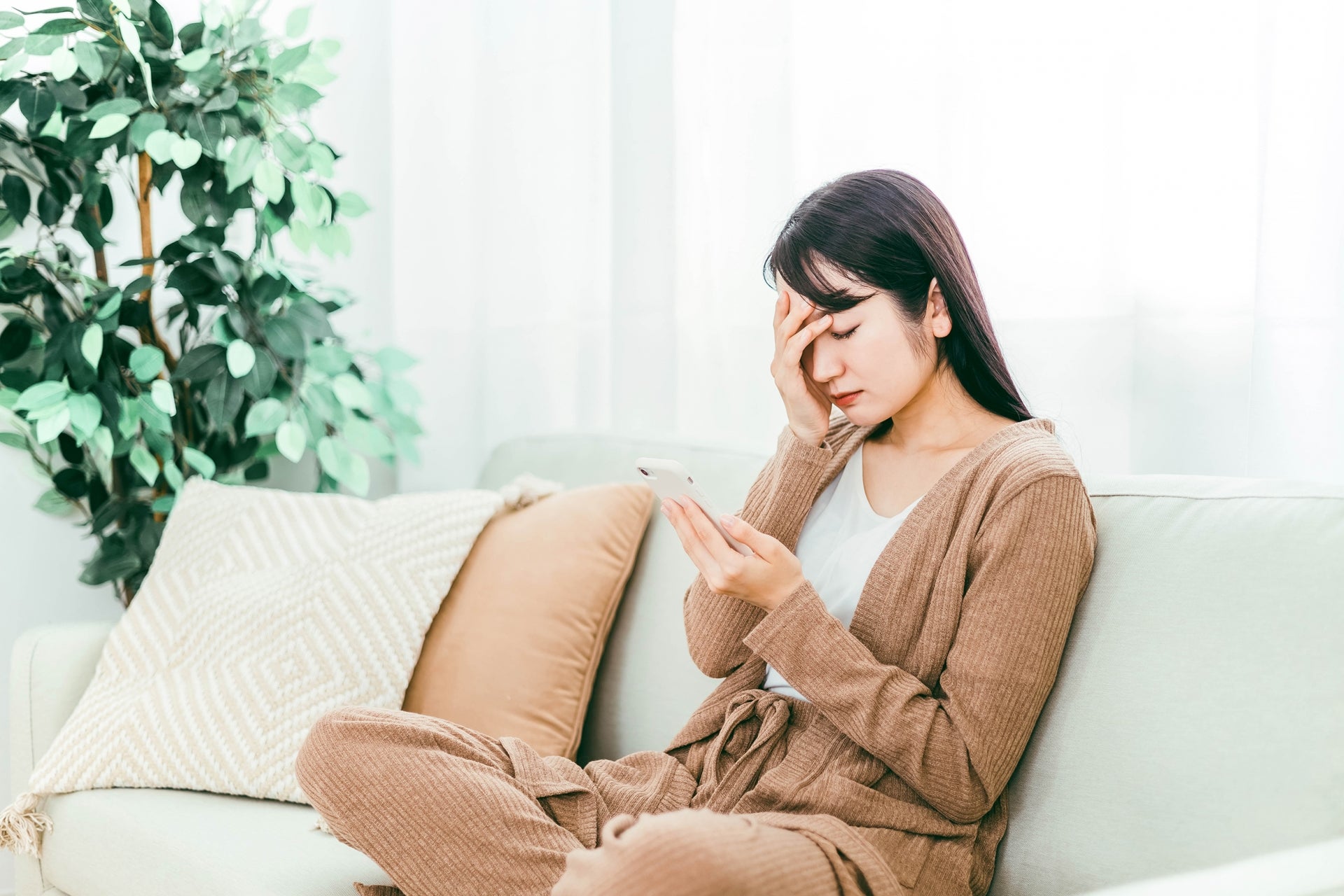 スマホを見ながら目を押さえる女性