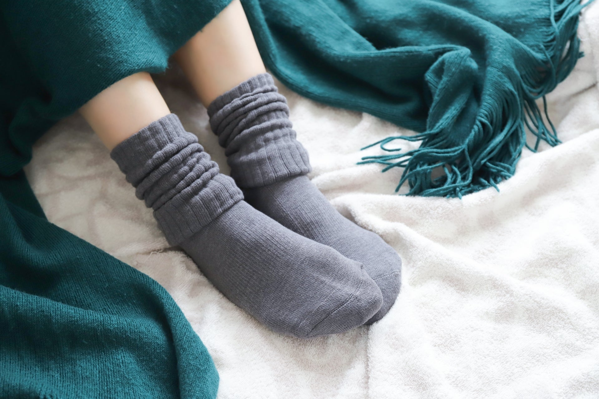 厚手の靴下とブランケットで体を温めている女性