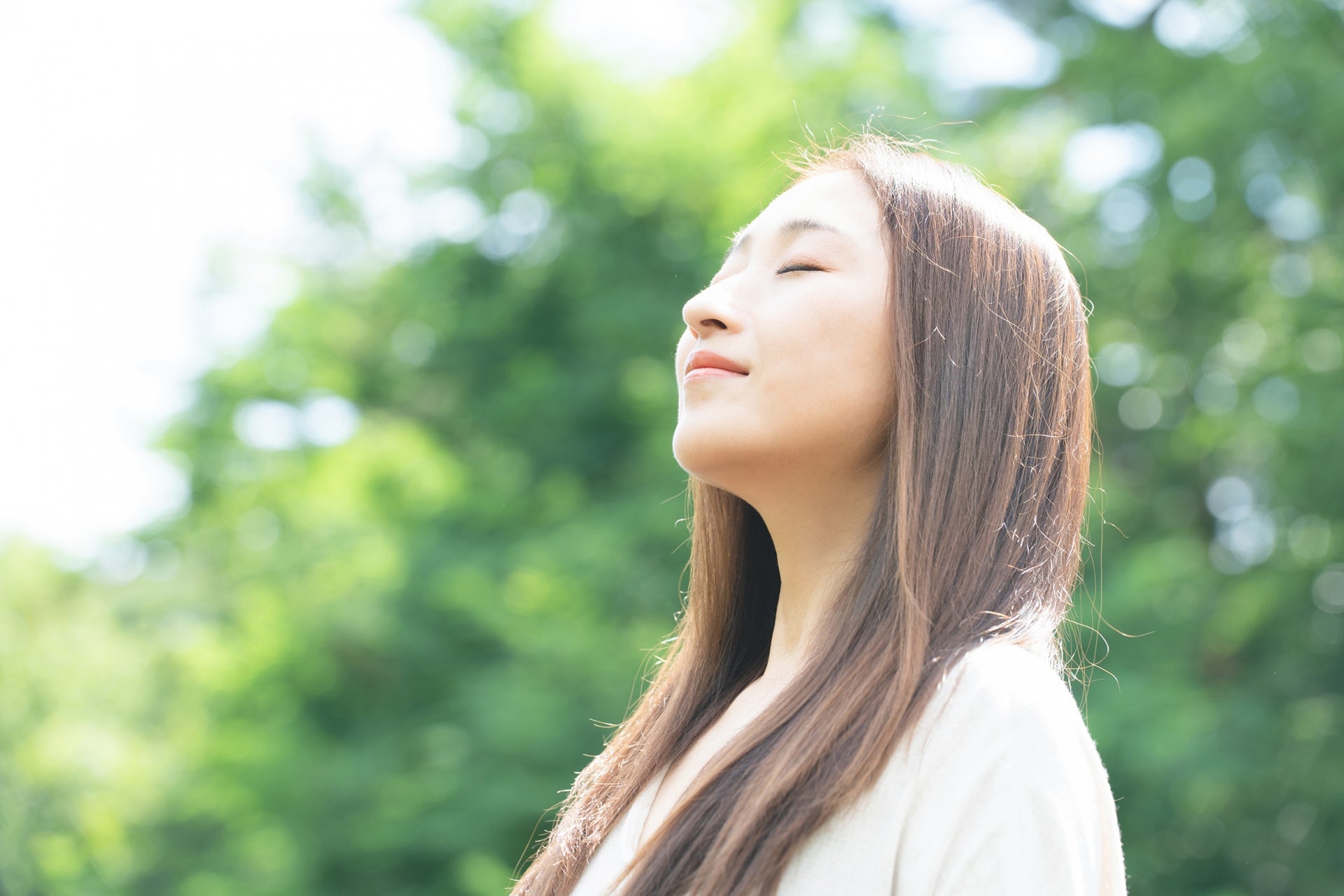 緑があふれる場所で深呼吸している女性