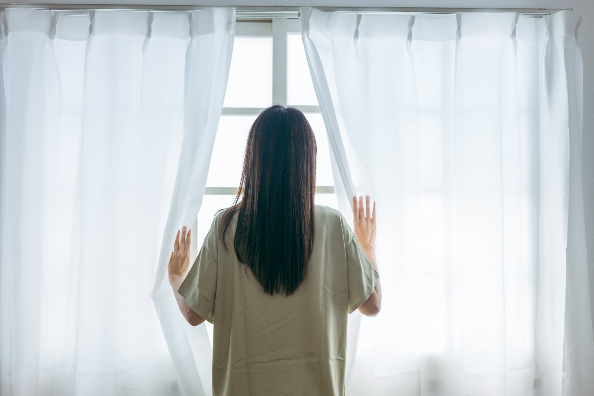 窓から外を眺める女性