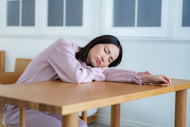 妊娠初期のストレスで机に伏せる人