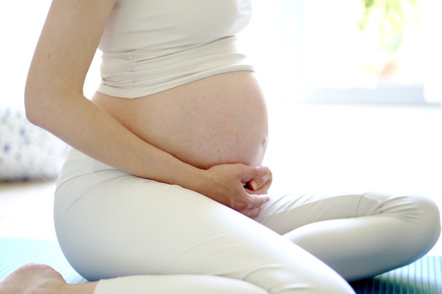 座り姿勢でお腹に手を添えるエクササイズ中の妊婦さん