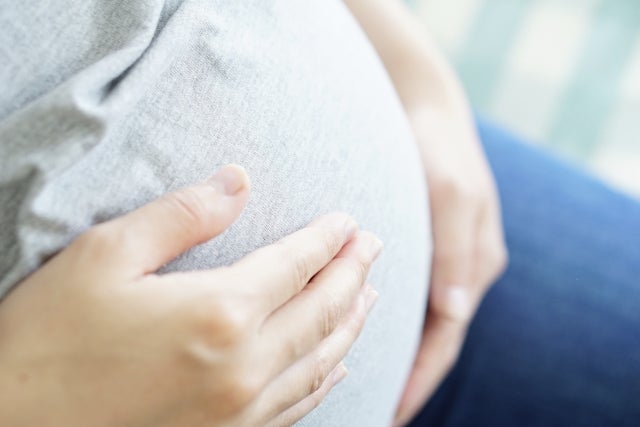 座ってお腹に手をあてている妊婦さん