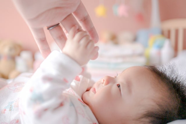 大人の手に触れる赤ちゃん