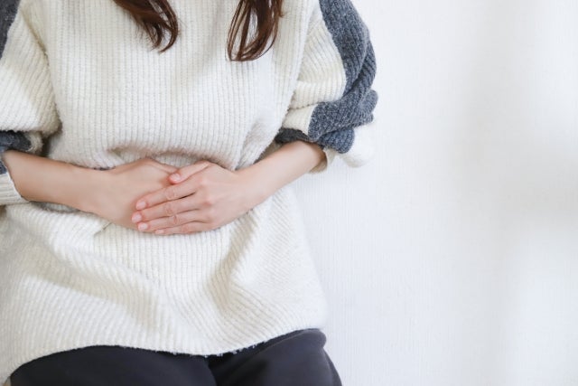 胃のあたりを痛そうに押さえる女性