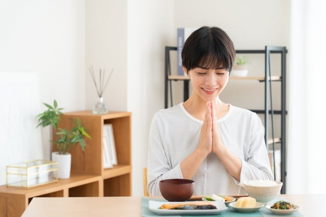 食事を前にして手を合わせる女性（いただきます）