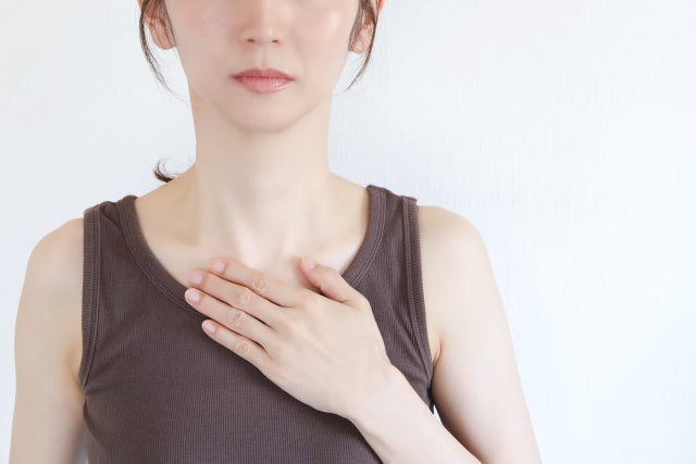 タンクトップ姿で胸に手を当てる女性