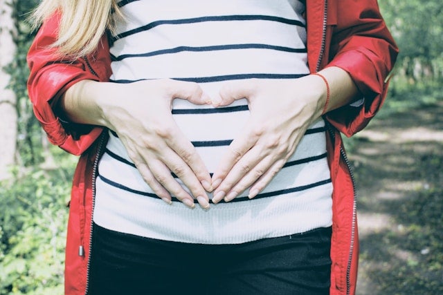 お腹の上で手でハートを作る妊婦さん