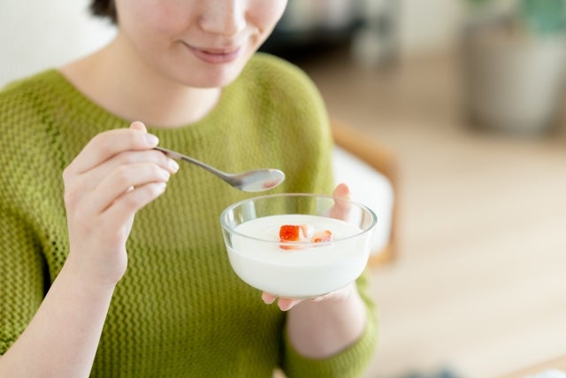 器に入ったヨーグルトをスプーンで食べようとしている女性