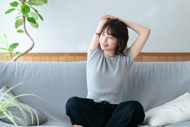 ソファに座りストレッチする人