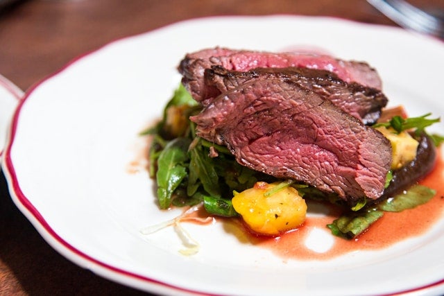 赤い縁の白い皿に盛り付けられたレアの肉