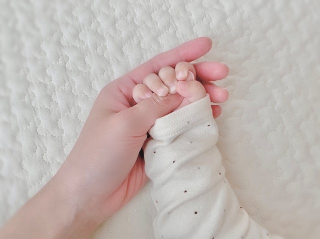 赤ちゃんてをやさしく包むママの手