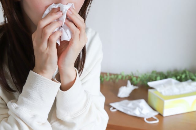 ティッシュで鼻をかんでいる女性