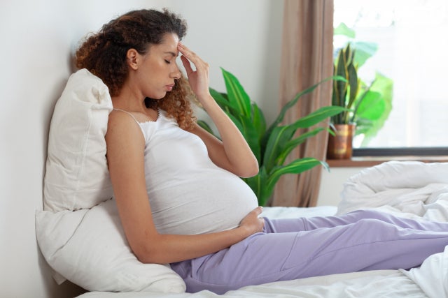 ベッドに座る体調が悪そうな妊婦さん