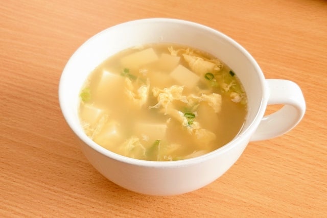 白いカップに入った卵と豆腐のスープ